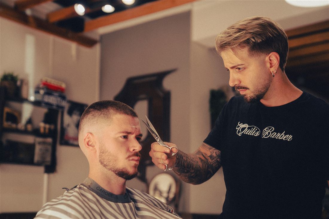 Víctor Quilis cortando el pelo con tijera a un cliente